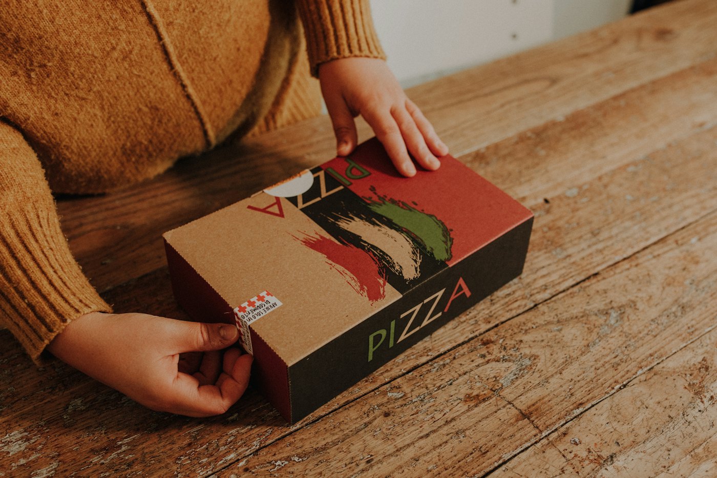 Pessoa abrindo a caixa de uma pizza recém-entregue
