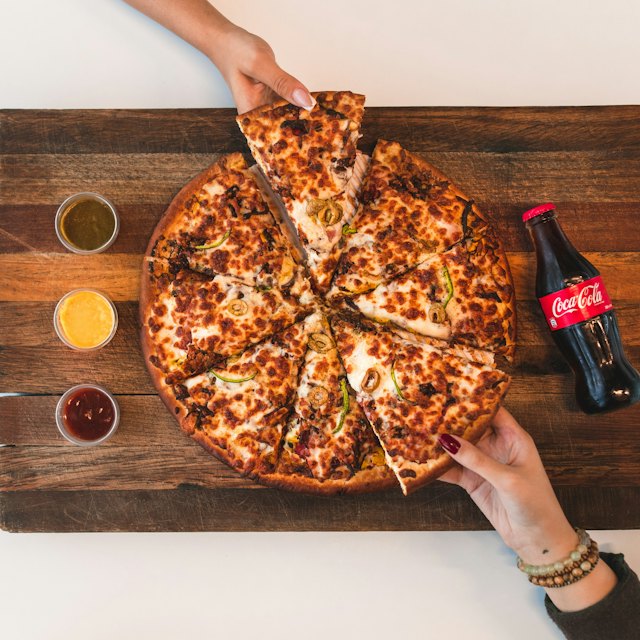 Pizza fatiada na tábua com refrigerante