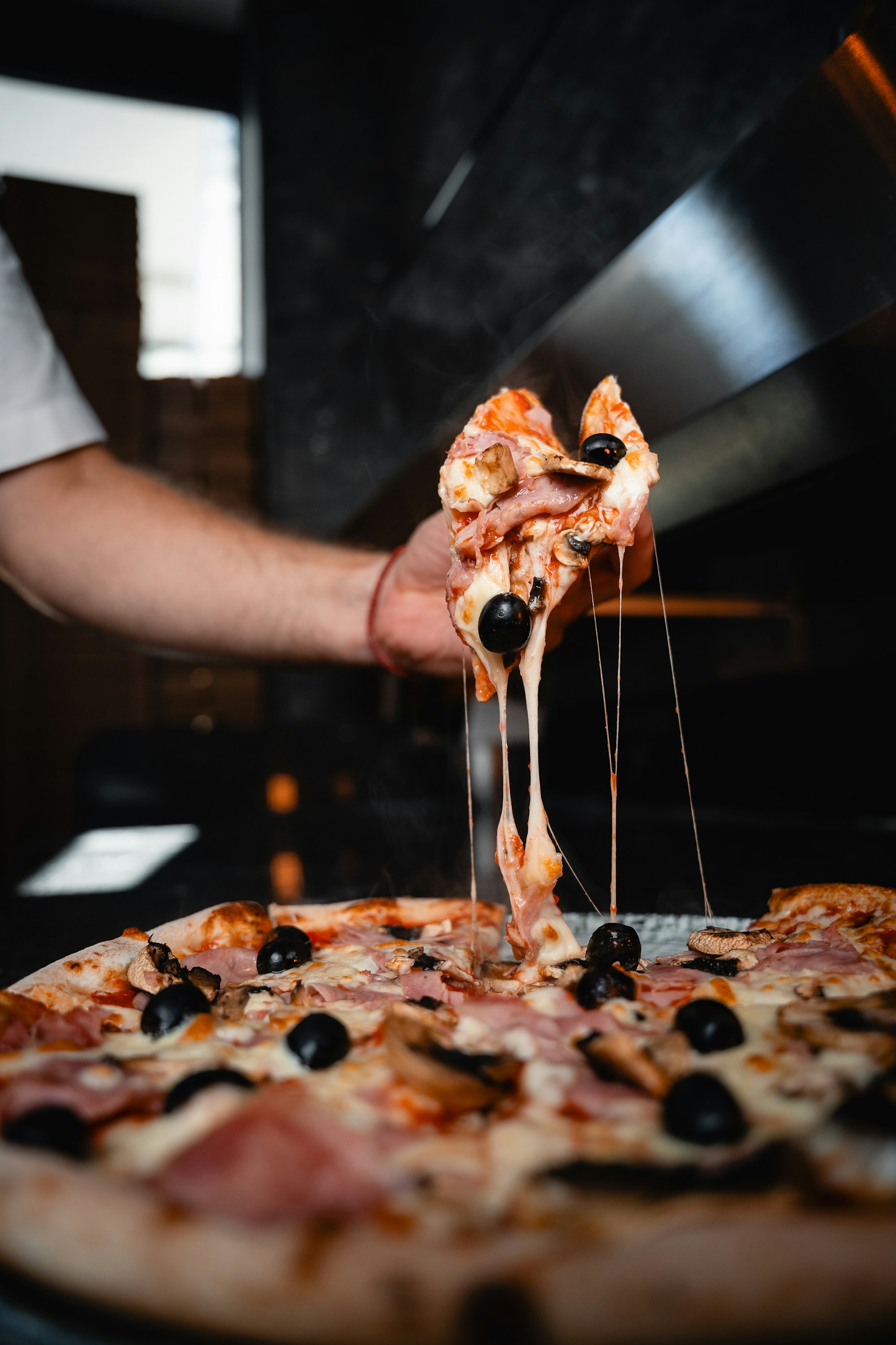 Fatia de pizza sendo puxada com o queijo derretido esticando
